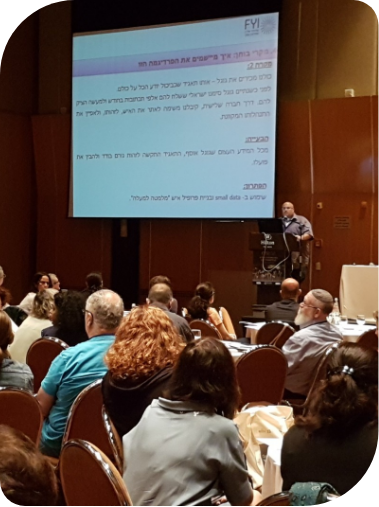 מרצה מ-FYI מציג בפני קהל בכנס מקצועי עם מצגת על שיטות הדרכה